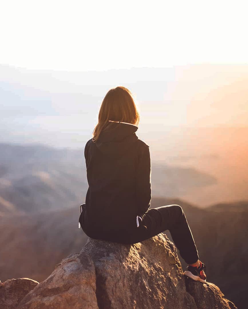 Lost-in-thought Woman Reflecting on top of Mountain